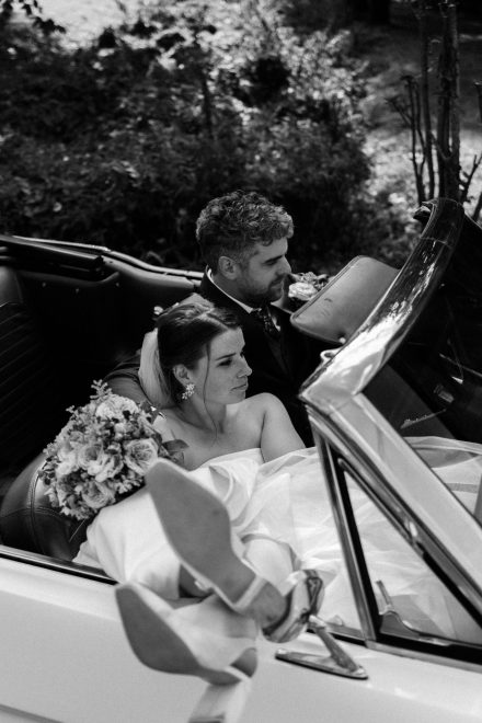 Bruidspaar in een klassieke cabriolet tijdens hun bruiloft