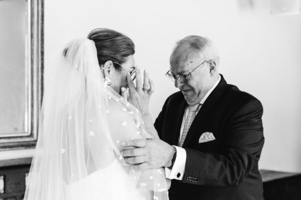 Emotioneel moment tussen vader en bruid op haar trouwdag – zwart-wit trouwfotografie die pure emotie vastlegt.